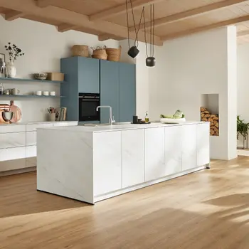 Küche mit weißer Kochinsel in Marmoroptik und blauen Hochschränken.